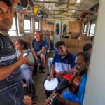Lokalny ludia hraju na hudobne nastroje vo vlaku z kandy do ella na Sri lanke.