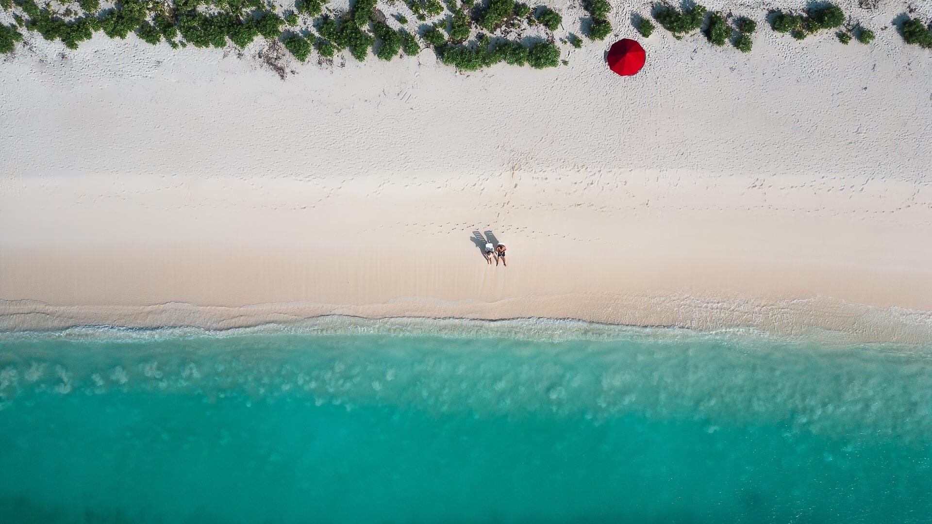 Tyrkysova plaz na ostrove Dhigurah, Maldivy s cervenym slnecnikom.